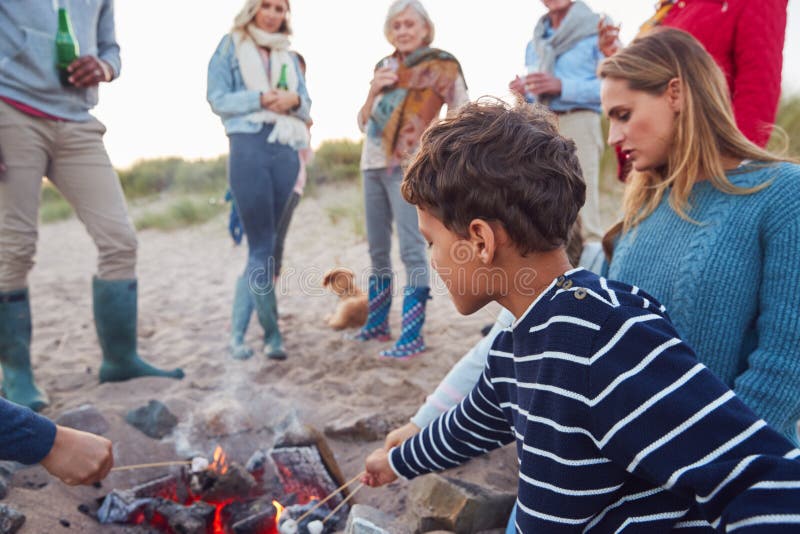 Multi-Generation Family Toasting Marshmallows Around Fire On Winter Beach Vacation stock photos