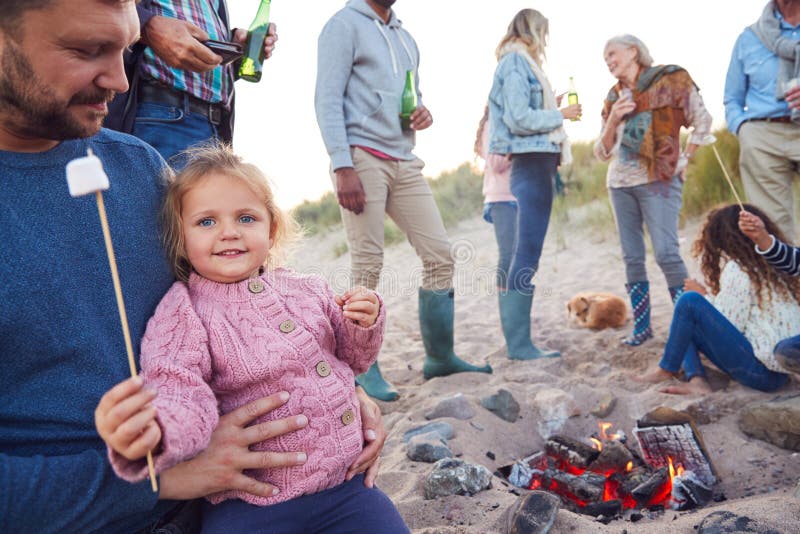 Multi-Generation Family Toasting Marshmallows Around Fire On Winter Beach Vacation royalty free stock photos