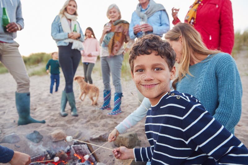 Multi-Generation Family Toasting Marshmallows Around Fire On Winter Beach Vacation stock images