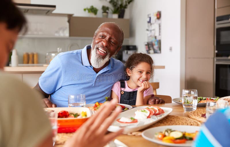 MultiGeneration Mixed Race Family Eating Meal Around Table at Home