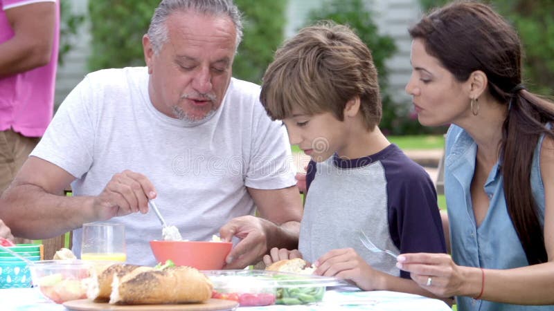 Multi Generations-Familie, die zusammen Mahlzeit im Garten genießt stock video Multi Generations-Familie, die zusammen Mahlzeit im Garten genießt stock video