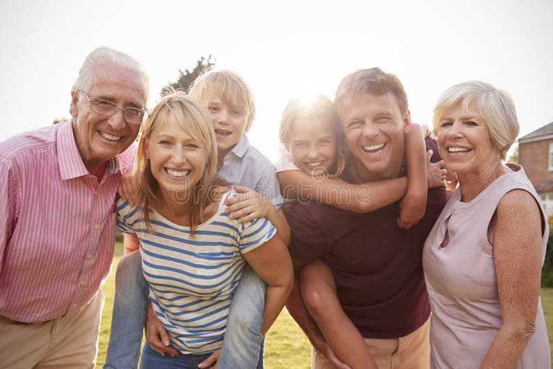 Multi Generationsfamilie im Gartenlächeln zur Kamera, Abschluss oben lizenzfreie stockfotografie Multi Generationsfamilie im Gartenlächeln zur Kamera, Abschluss oben lizenzfreie stockfotografie