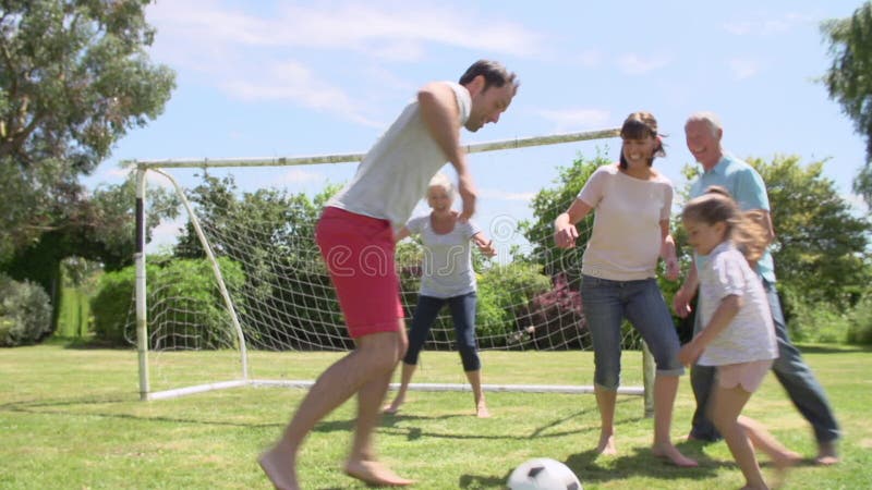 Multi geração que joga o futebol no jardim junto