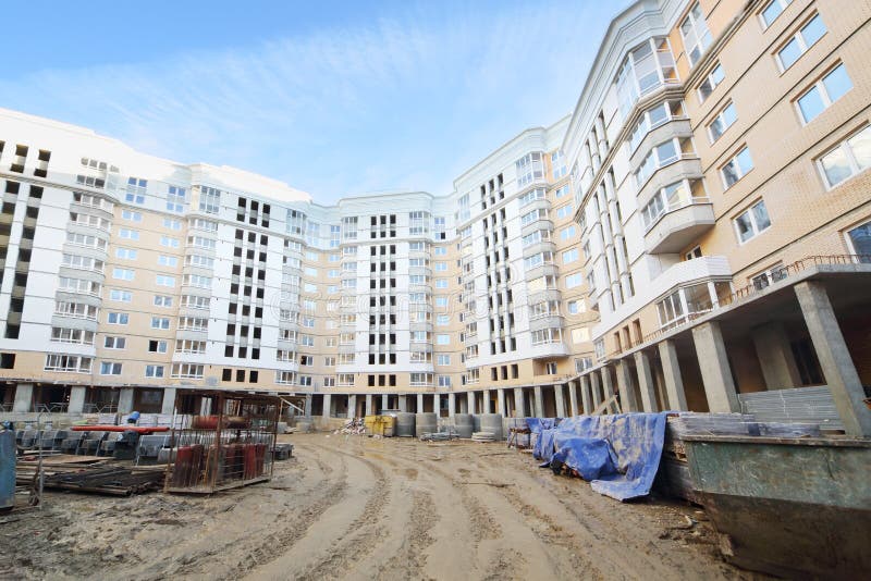 Multi-storey building under construction and concrete structures on ground at day.