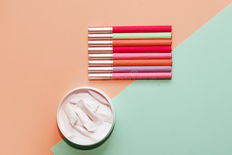 Multicolored Cigarettes and Snus Pads on a Paper Background the