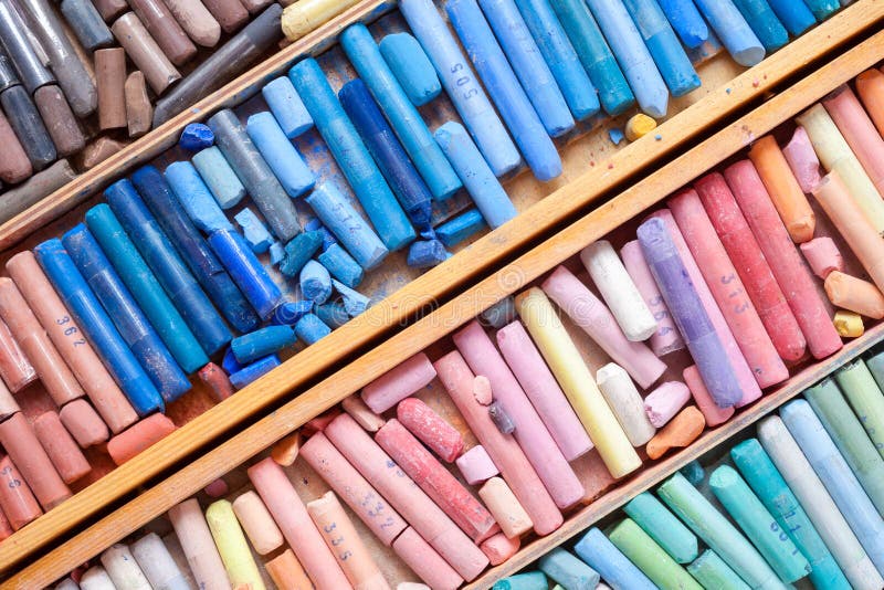 Multicolored pastel crayons in wooden artist box closeup