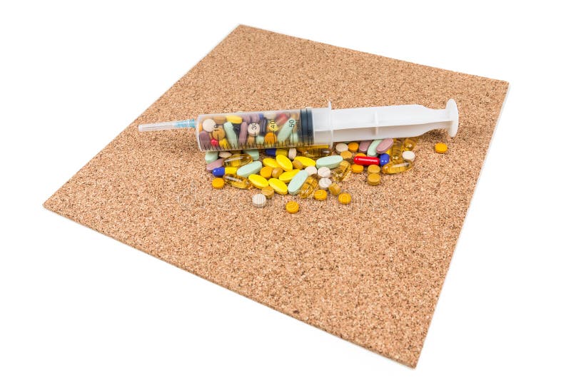 Multicolored pillen in een grote spuit over cork royalty-vrije stock afbeeldingen Multicolored pillen in een grote spuit over cork royalty-vrije stock afbeeldingen