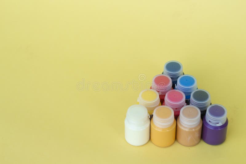 Multicolored plastic cans with acrylic paint on a yellow background. Art supplies. Set for the artist. royalty free stock images Multicolored plastic cans with acrylic paint on a yellow background. Art supplies. Set for the artist. royalty free stock images
