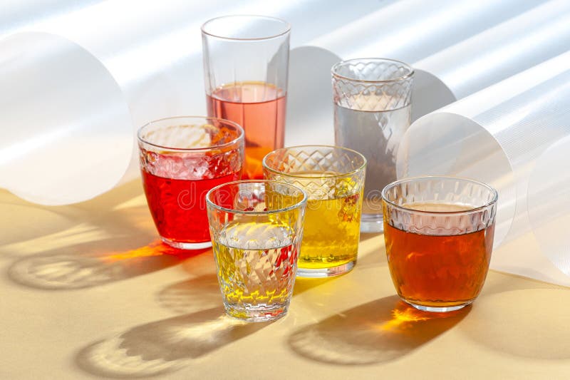 Multicolored Soft Drinks in Glass Cut Glasses on a Yellow Table Stock