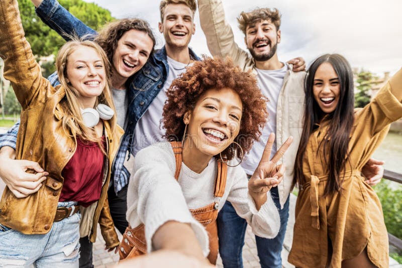 Multicultural best friends having fun taking group selfie portrait outside - Smiling guys and girls celebrating party