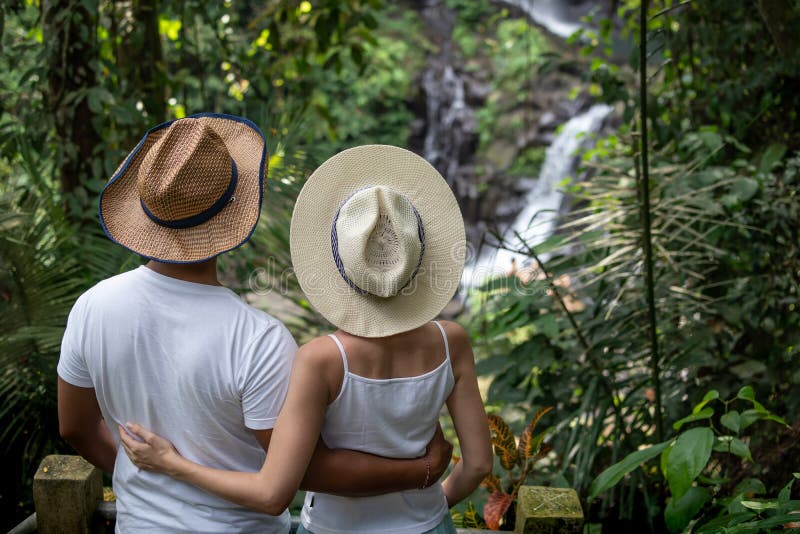 Multicultural couple enjoying waterfall scenery in tropical rainforest. Young mixed race couple on vacation in Asia. Pengibul stock photos Multicultural couple enjoying waterfall scenery in tropical rainforest. Young mixed race couple on vacation in Asia. Pengibul stock photos