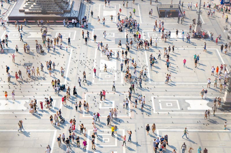 Milan, Italy, September 9, 2018: Crowd of small figures of many people are walking and a lot of pigeons on Piazza del Duomo square in historical city centre, top view from the roof of Milano cathedral. Milan, Italy, September 9, 2018: Crowd of small figures of many people are walking and a lot of pigeons on Piazza del Duomo square in historical city centre, top view from the roof of Milano cathedral