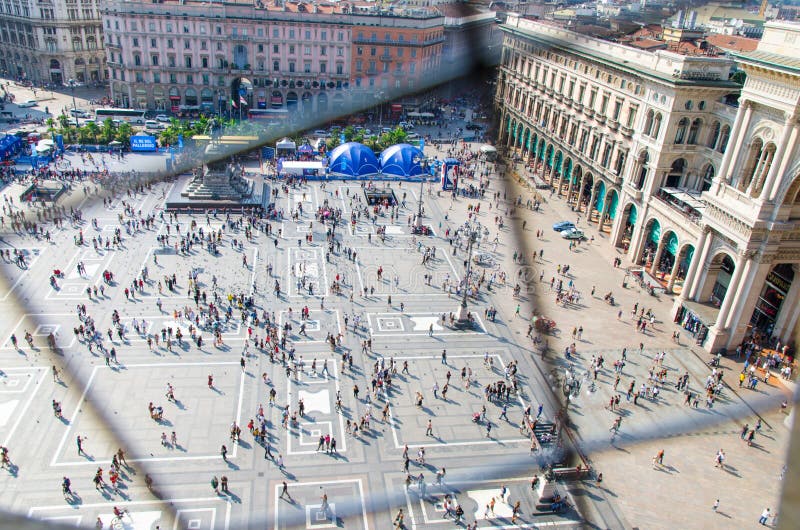 Milan, Italy, September 9, 2018: Crowd of small figures of people are walking on Piazza del Duomo square near Gallery Vittorio Emanuele II in historical centre, top view from Duomo di Milano cathedral. Milan, Italy, September 9, 2018: Crowd of small figures of people are walking on Piazza del Duomo square near Gallery Vittorio Emanuele II in historical centre, top view from Duomo di Milano cathedral