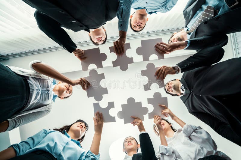 Multiethnic business people holding jigsaw pieces together. Habiliment stock photo