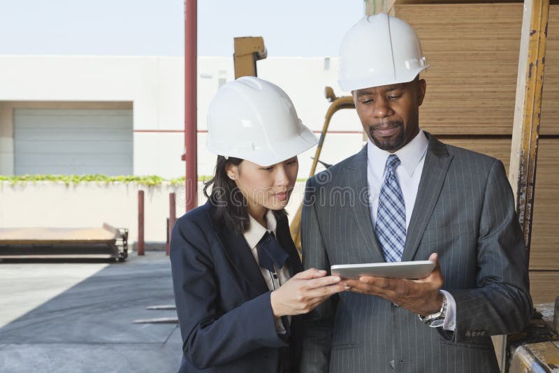 Multiethnic contractors using tablet PC at timber yard royalty free stock photos Multiethnic contractors using tablet PC at timber yard royalty free stock photos