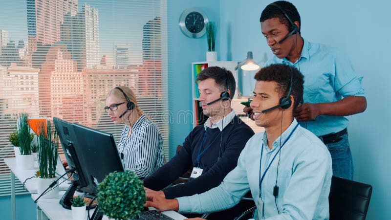Multiethnic customer service representative telling his colleagues a joke while calling to the clients stock image