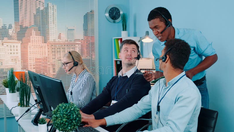 Multiethnic customer service representative telling his colleagues a joke while calling to the clients royalty free stock image