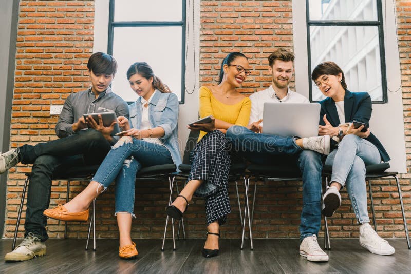 Multiethnic diverse group of young and adult people using smartphone, laptop computer, digital tablet together