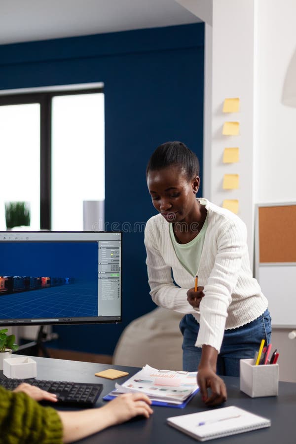Multiethnic women designer looking at computer with dual displays stock photos