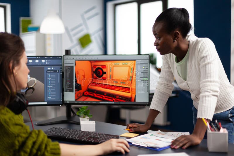 Multiethnic women designer looking at computer with dual displays stock photo