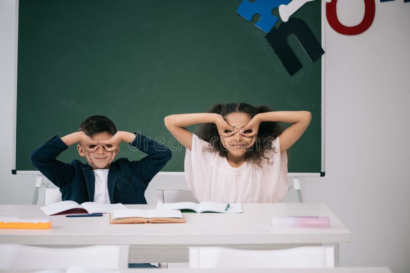 Multiethnische Schüler, die Spaß beim am Schreibtisch zusammen sitzen in der Klasse haben stockbild Multiethnische Schüler, die Spaß beim am Schreibtisch zusammen sitzen in der Klasse haben stockbild
