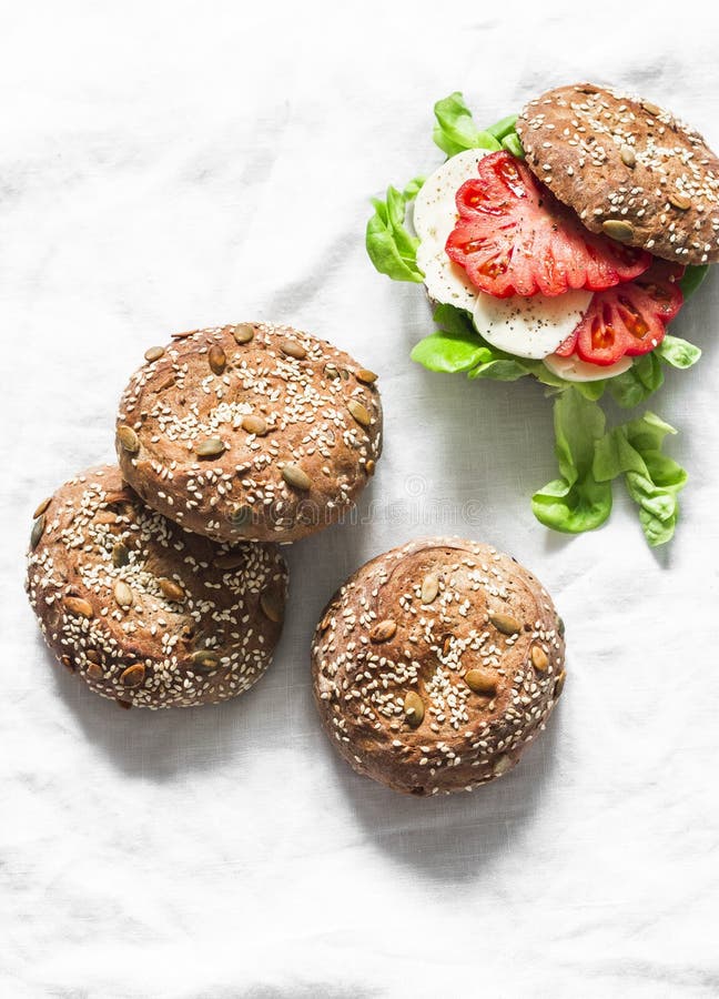 Multigrain multiseed fitness buns and green salad tomato homemade cheese sandwich on light background, top view. Healthy diet food stock image Multigrain multiseed fitness buns and green salad tomato homemade cheese sandwich on light background, top view. Healthy diet food stock image