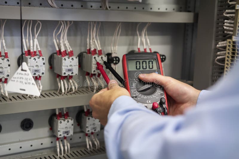 Multimeter i händer av elektrikercloseupen Service arbetar i elektrisk ask Underhåll av den elektriska panelen