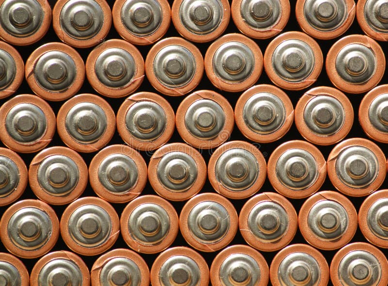 A Horizontal View of AA batteries grouped together. Multiple AA batteries grouped together forming a pattern of rows and columns of positive terminals.
