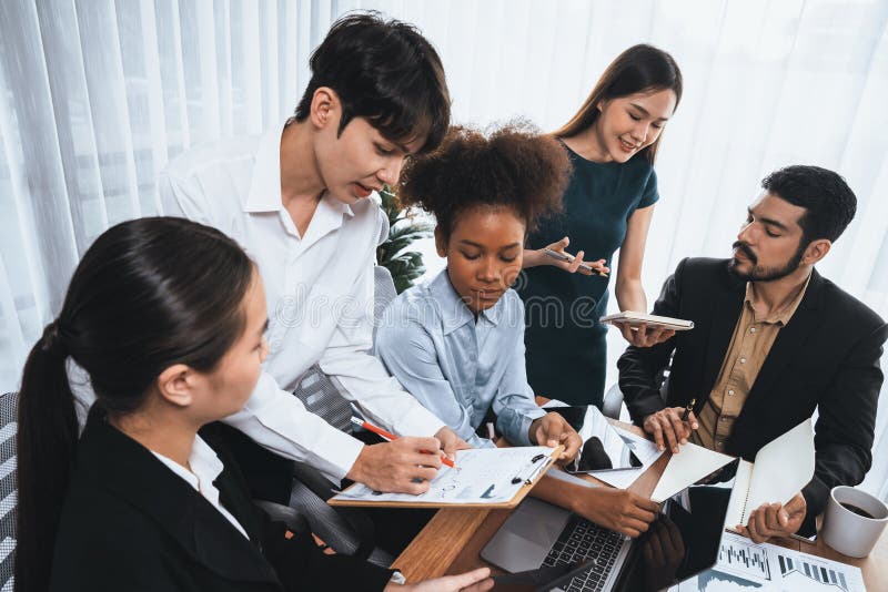 Multiracial analyst team use BI dashboard for data analysis. Concord. Multiracial analyst team use BI dashboard data to analyze financial report on meeting table. Group of diverse business people utilize data analysis by FIntech for business marketing decision.