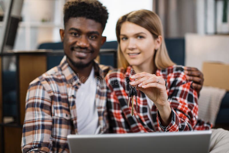Multiracial family with laptop holding keys from new flat royalty free stock photo