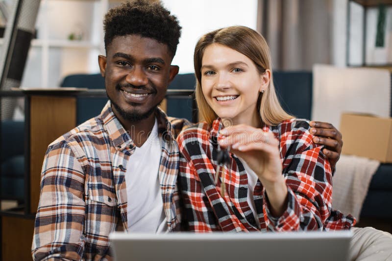 Multiracial family with laptop holding keys from new flat royalty free stock photos