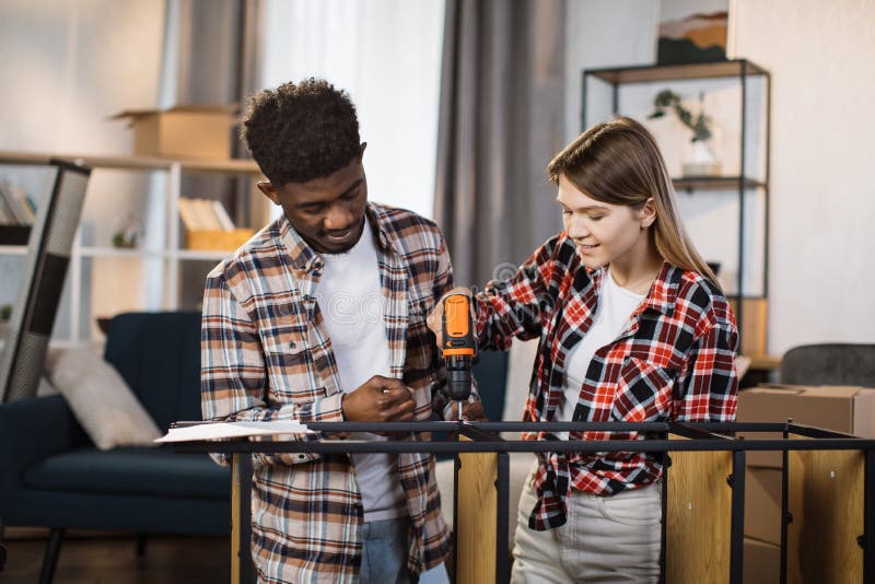 Multiracial family using screwdriver for assembling shelves stock photos