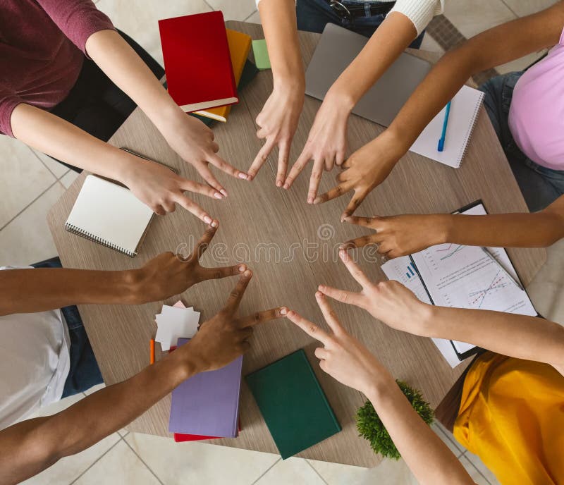 Multiracial students joining victory signs in circle, top view stock image Multiracial students joining victory signs in circle, top view stock image
