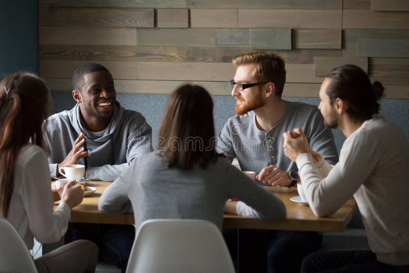 Multiraciale millennial vrienden die het drinken koffie samen spreken royalty-vrije stock afbeeldingen Multiraciale millennial vrienden die het drinken koffie samen spreken royalty-vrije stock afbeeldingen