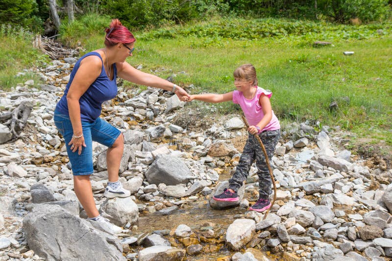 Mum Helps Her Daughter To Cross a Mountain Stream Stock Ph
