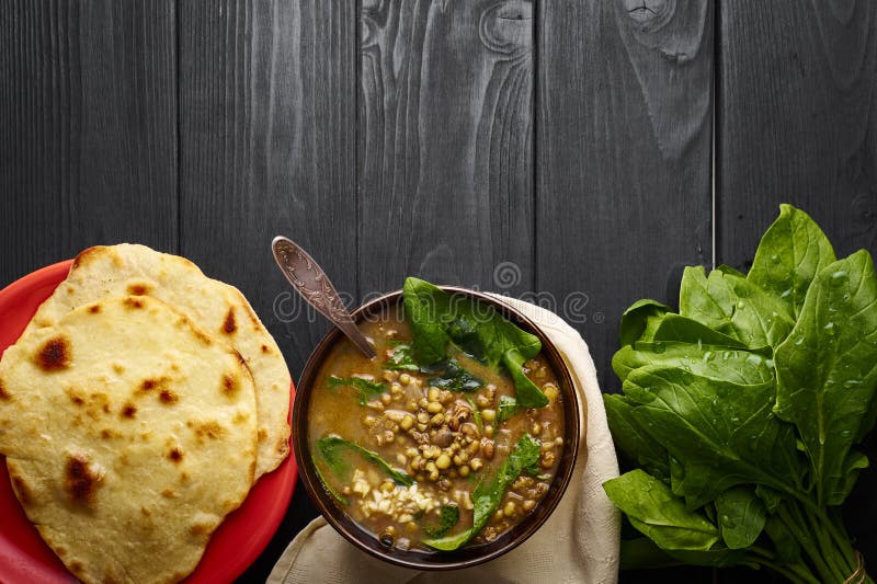 Mung Dhal with green Spinach and Chapati at black wooden table. Moong Dal Indian Cuisine curry. Vegetarian spicy dish stock photography