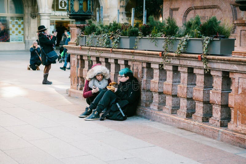 Munich, Germany, December 29, 2016: Two punk girls sit and eat in the central square in Munich. Subculture. Everyday stock photo Munich, Germany, December 29, 2016: Two punk girls sit and eat in the central square in Munich. Subculture. Everyday stock photo