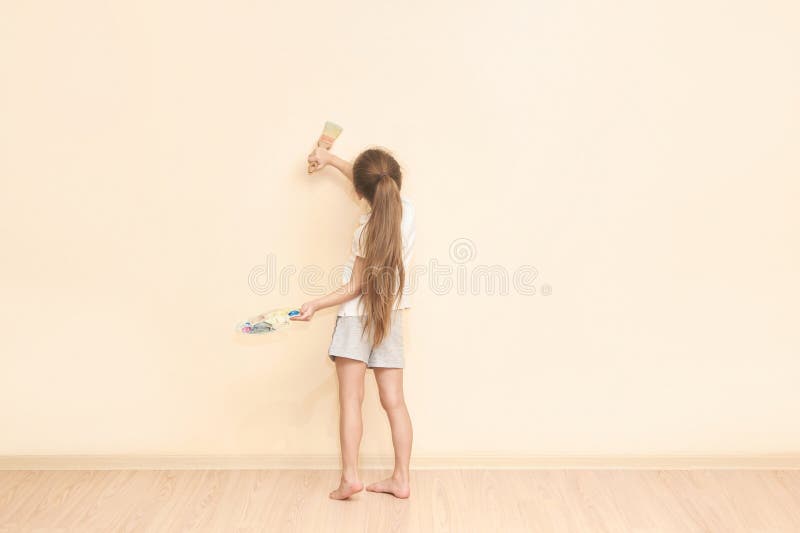 Mur de peinture de jeune fille caucasienne avec brosse dans l'intérieur minimaliste de la chambre photographie stock