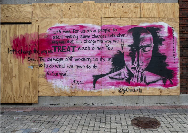 Pictured is one of many murals painted on plywood in Deep Ellum after the George Floyd protests.  The mural features words and the face of Shakur Tupac.  Tupac was considered by many to be one of the most significant rappers of all time and is considered a symbol of resistance and activism against inequality.  He was murdered in 1996 in a drive-by shooting in Las Vegas.  In May 2020 several businesses in Deep Ellum were vandalized and looted following a protest in downtown Dallas. A peaceful protest over the killing of George Floyd turned violent when a small group clashed with police, broke out windows, looted businesses and set fires.  Because of fear of looting many business put up plywood protection of their doors or windows.  Subsequently artists painted black lives themed murals on the protective plywood all over Deep Ellum.  After the 1850sâ€™ slave liberation in Texas, many slaves from Texas and nearby states built their houses and cropped their land in the future Deep Ellum, which was one of the largest African-American communities. This community holds the most history in the Dallas area.  Today it is composed largely of arts and entertainment venues and is known for it`s graffiti, street art and murals.  It is located near downtown in East Dallas, Texas. Pictured is one of many murals painted on plywood in Deep Ellum after the George Floyd protests.  The mural features words and the face of Shakur Tupac.  Tupac was considered by many to be one of the most significant rappers of all time and is considered a symbol of resistance and activism against inequality.  He was murdered in 1996 in a drive-by shooting in Las Vegas.  In May 2020 several businesses in Deep Ellum were vandalized and looted following a protest in downtown Dallas. A peaceful protest over the killing of George Floyd turned violent when a small group clashed with police, broke out windows, looted businesses and set fires.  Because of fear of looting many business put up plywood protection of their doors or windows.  Subsequently artists painted black lives themed murals on the protective plywood all over Deep Ellum.  After the 1850sâ€™ slave liberation in Texas, many slaves from Texas and nearby states built their houses and cropped their land in the future Deep Ellum, which was one of the largest African-American communities. This community holds the most history in the Dallas area.  Today it is composed largely of arts and entertainment venues and is known for it`s graffiti, street art and murals.  It is located near downtown in East Dallas, Texas.