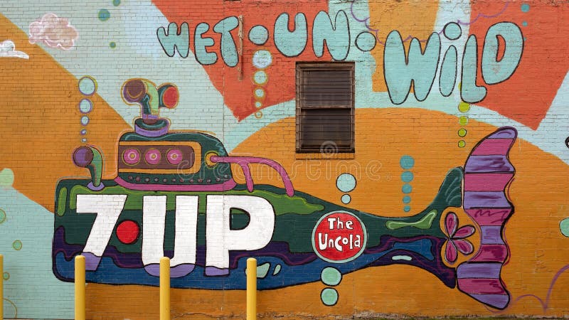 Pictured is a colorful two story mural painted to advertise Tom Thumb Express and 7-Up in Dallas, Texas.  The talented mural artist is Lesli Marshal working with exploredinary, a creative agency that blends the talents and aesthetics of artists Sarah Reyes and Daniel Driensky.  The mural includes a grocer, cup of coffee, donut, popcorn, hot dog, milk and cookie. Pictured is a colorful two story mural painted to advertise Tom Thumb Express and 7-Up in Dallas, Texas.  The talented mural artist is Lesli Marshal working with exploredinary, a creative agency that blends the talents and aesthetics of artists Sarah Reyes and Daniel Driensky.  The mural includes a grocer, cup of coffee, donut, popcorn, hot dog, milk and cookie.