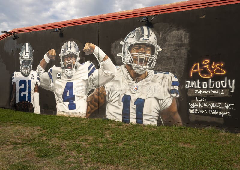 Pictured is a mural featuring Dallas Cowboy stars Ezekiel Elliot number 21, Dak Prescott number 4, and Micah Parsons number 11.  The artist is Juan Velazquez and the location is AJ`s Autobody, a business in Grand Prairie, Texas. Pictured is a mural featuring Dallas Cowboy stars Ezekiel Elliot number 21, Dak Prescott number 4, and Micah Parsons number 11.  The artist is Juan Velazquez and the location is AJ`s Autobody, a business in Grand Prairie, Texas.