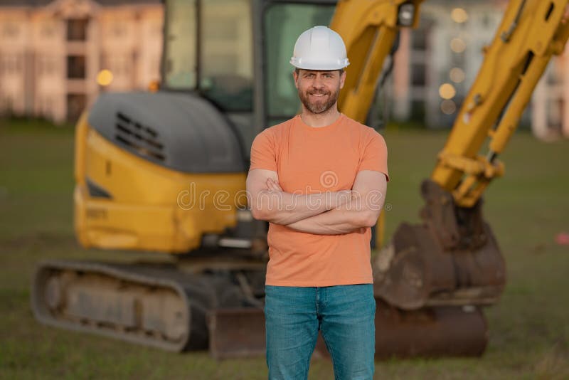Muratore in casco presso il cantiere. operaio di ingegneria industriale a hardhat vicino a bulldozer o fotografie stock