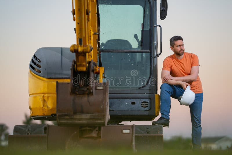 Muratore caucasico a casco nel cantiere. operaio di ingegneria industriale a hardhat vicino a bulldozer o fotografia stock libera da diritti