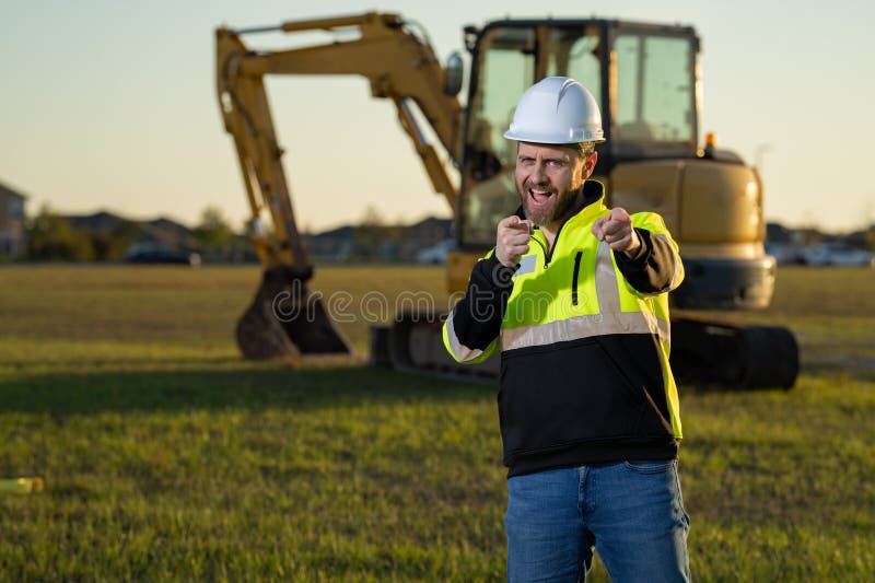 Muratore caucasico a casco nel cantiere. operaio di ingegneria industriale a hardhat vicino a bulldozer o fotografia stock