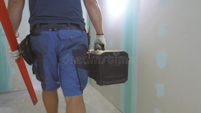 Muratore che cammina attraverso l'appartamento con la cassetta portautensili