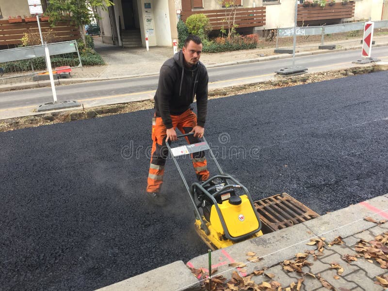Muratore che per mezzo di un compattatore del piatto fotografie stock libere da diritti Muratore che per mezzo di un compattatore del piatto fotografie stock libere da diritti