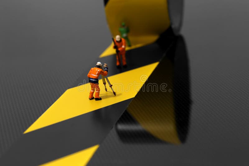 Muratori miniatura del modello di scala che per mezzo del nastro di rischio fotografia stock Muratori miniatura del modello di scala che per mezzo del nastro di rischio fotografia stock