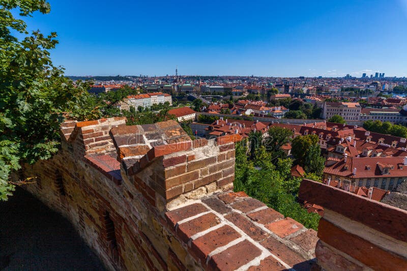 Murowana ściana z widokiem na miasto, na której widoczne są czerwone dachy, budynki i odległa panorama pod jasnym niebem z zieleni zdjęcia royalty free