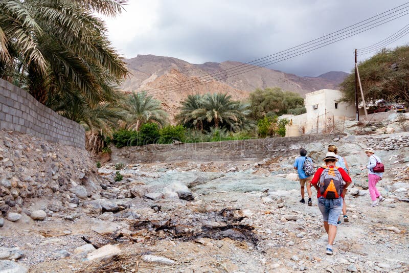 Muscat Oman - December 16, 2018: gruppen av turister promenerar wadin - en torkad övre flodbädd - i utkanten av Muscat royaltyfri fotografi Muscat Oman - December 16, 2018: gruppen av turister promenerar wadin - en torkad övre flodbädd - i utkanten av Muscat royaltyfri fotografi