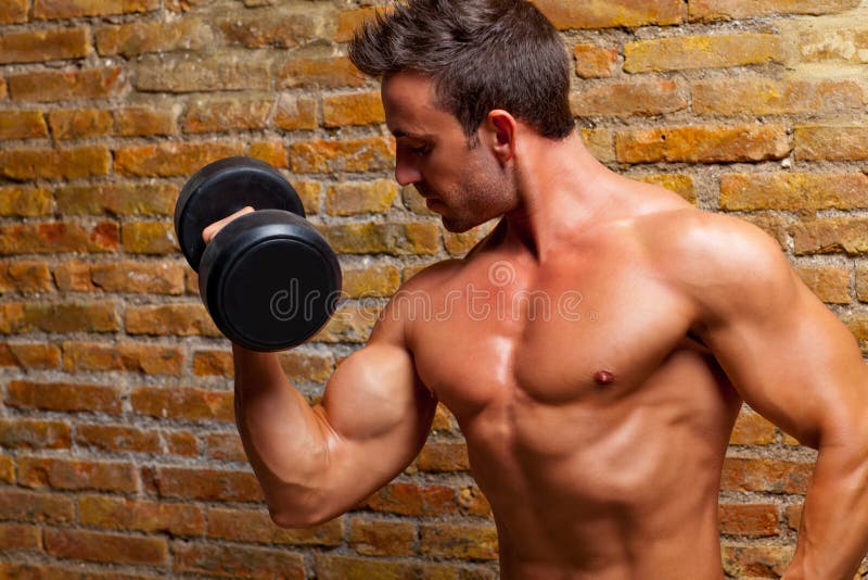 Muscle l'uomo a forma di del corpo con i pesi sul muro di mattoni
